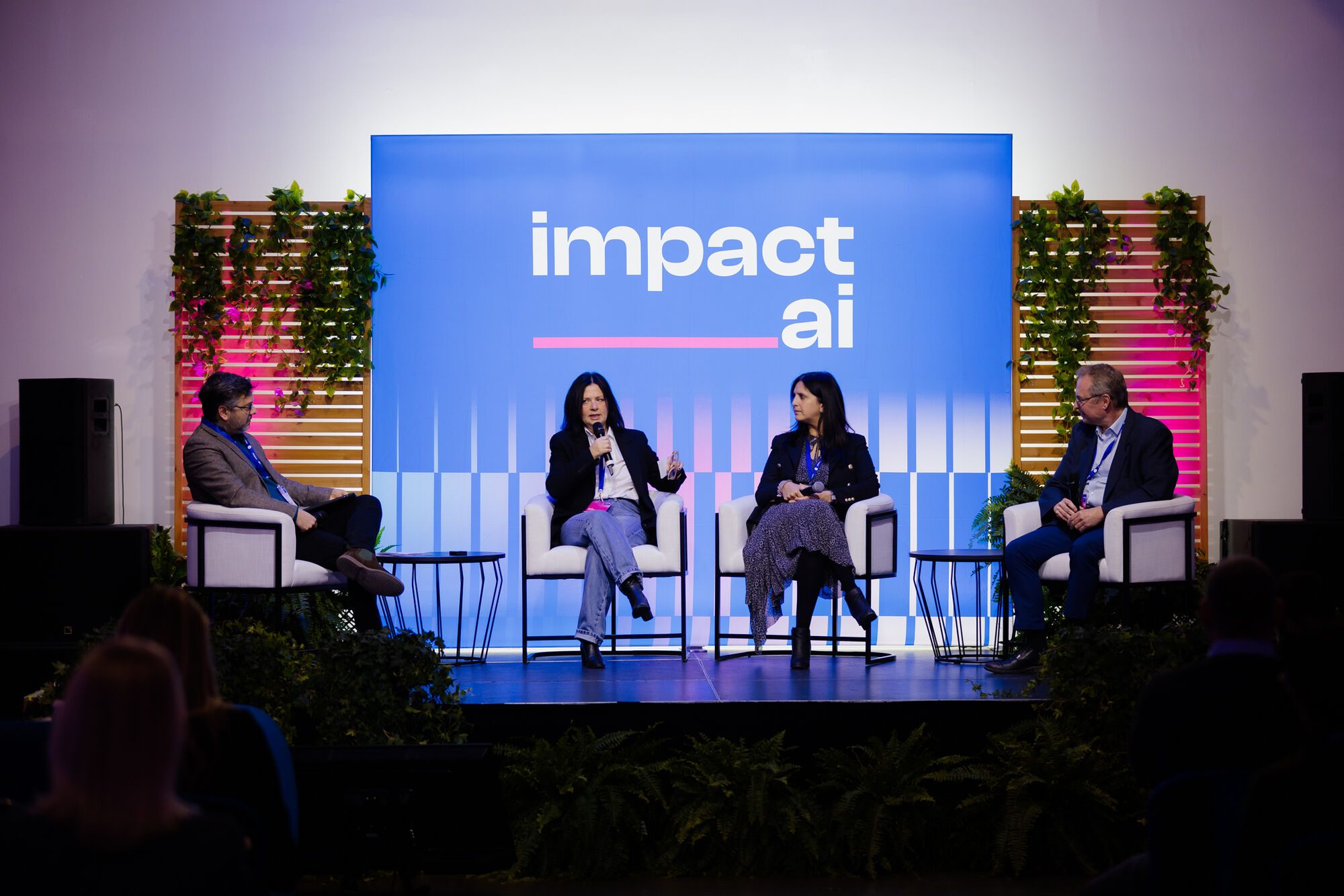 Table ronde sur scène : quatre personnes assises devant l’écran « impact ai »