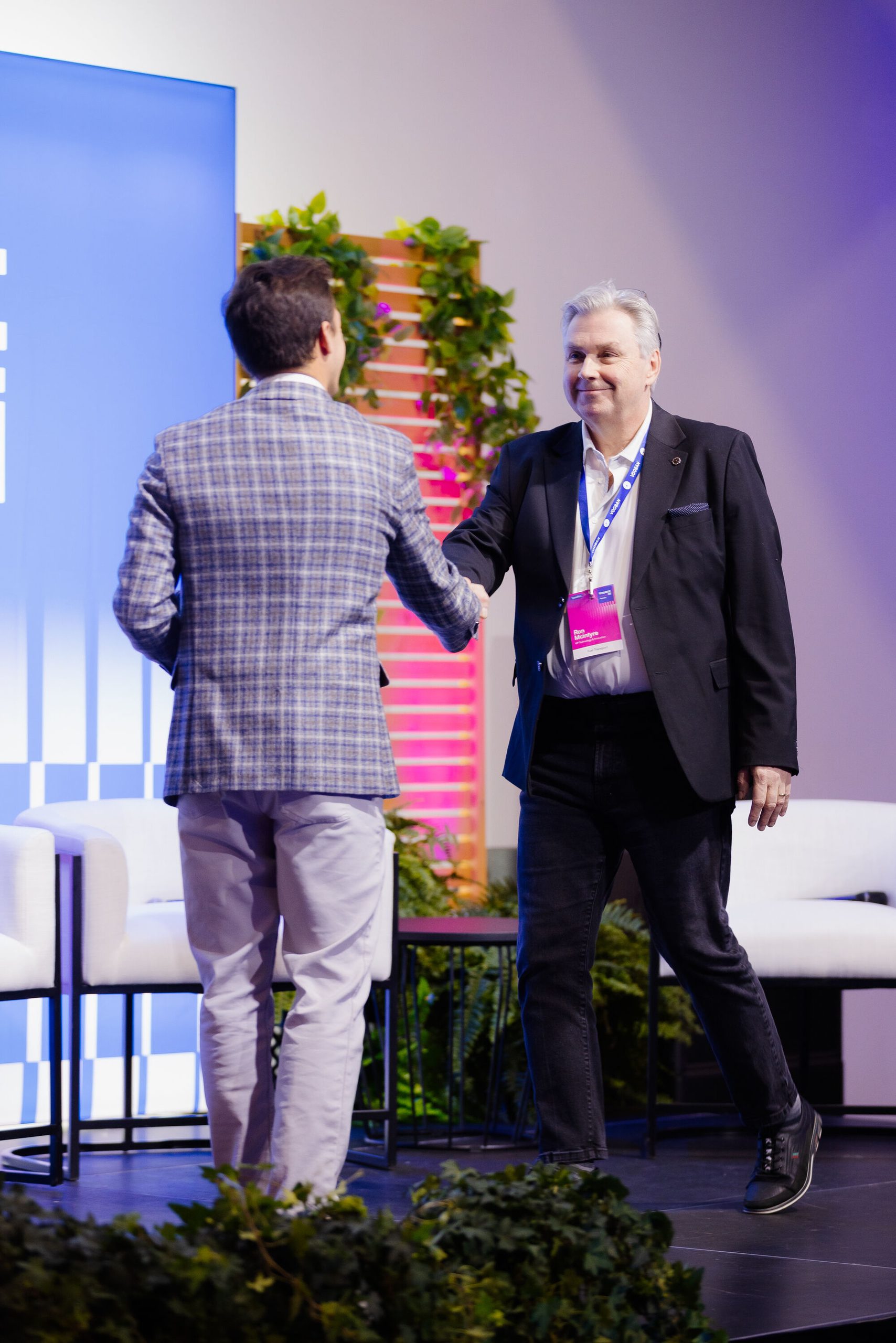 Ron Mcintyre, de Fuel Transport, serre la main d’un homme vu de dos sur la scène d’Impact AI