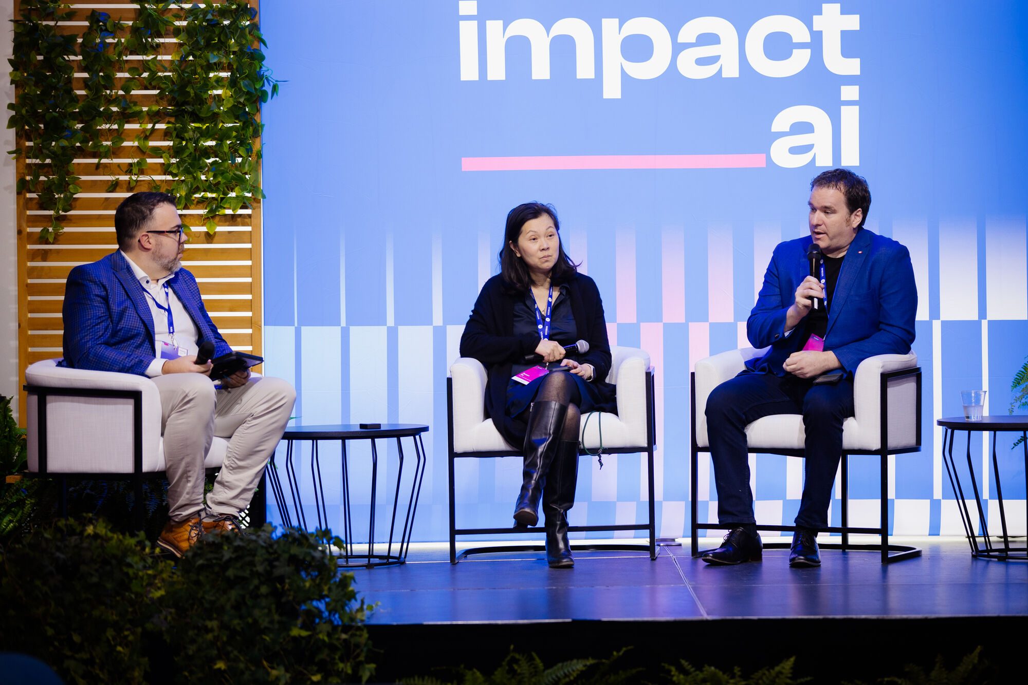 Kevin Moore, à gauche, anime un panel de deux invités sur la scène d’Impact AI ; l’un d’eux parle au micro