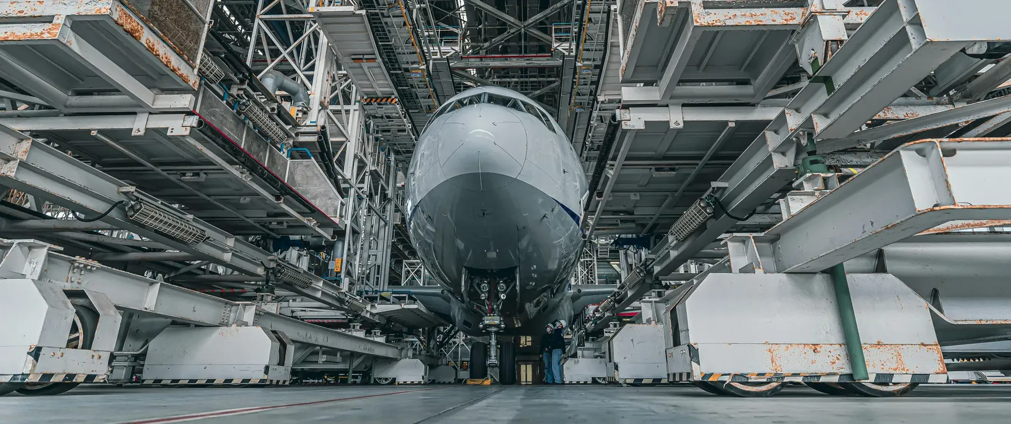 Airliner undergoing heavy maintenance in a hangar, surrounded by multi-level access platforms.